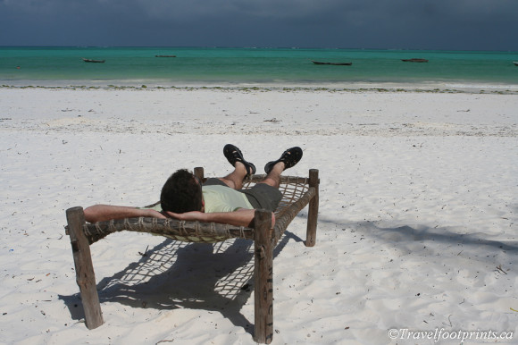 man relaxing in lounge chair on paje beach zanzibar