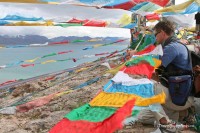 man-placing-prayer-flags-nam-tso-lake-tibet